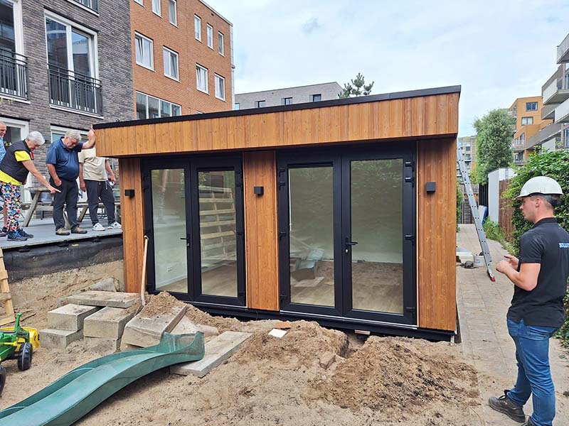 Moderne houten tuinkamer met glazen deuren wordt geplaatst op schroeffundering in Amsterdam