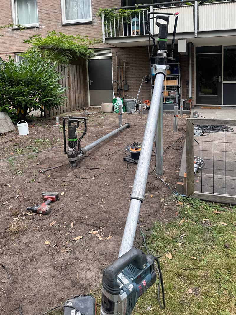 ingedraaide-schroeffundering-stadstuin-amsterdam-van-aken Handmachine voor schroeffunderingen in gebruik op moeilijk bereikbare locatie Amsterdam met compact boorgereedschap