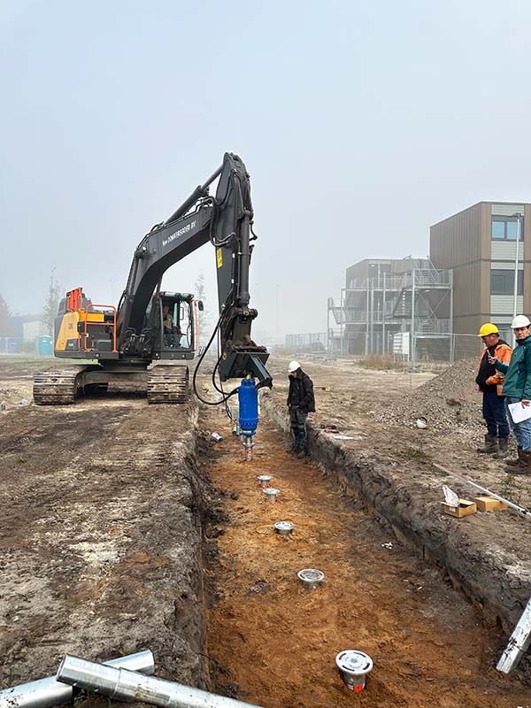 Plaatsing van circulaire stalen schroeffunderingen voor een emissiearm bouwproject, trillingvrij en zonder graafwerk. Herbruikbare funderingspalen van staal geïnstalleerd als lage-impact fundering voor flexwoningen